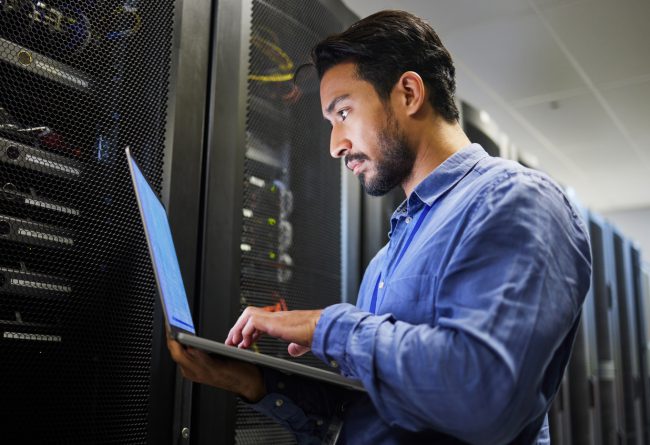Connectivity, data center and a man with a laptop for maintenance, cyber security and internet check. Coding, email and an Asian programmer typing on a computer for network or server analytics